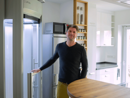 Jüngerer Mann steht vor eingebautem Homelift in moderner Wohnung