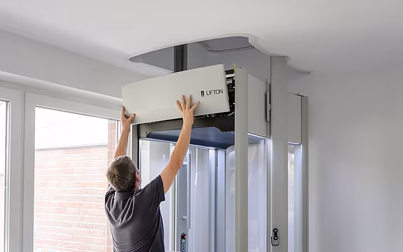Ein Mitarbeiter von LIFTON bringt die Verkleidung an das Elektronikgehäuse des Homelifts an.