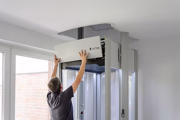 Ein Mitarbeiter von LIFTON bringt die Verkleidung an das Elektronikgehäuse des Homelifts an.
