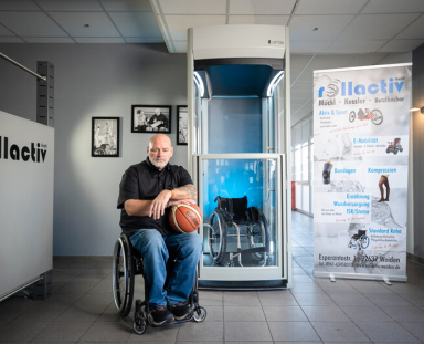 Das sagen unsere Partner: Sanitätshaus rollactiv Mann sitzt im Rollstuhl mit einem Basketball in der Hand vor einem Homelift