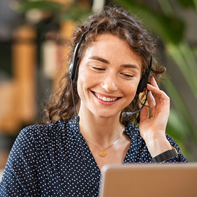 Junge Frau telefoniert mit Headset am Laptop